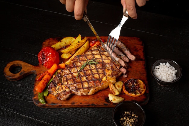 Grilled beef steak on the dark wooden surface.