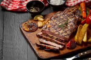 Free photo grilled beef steak on the dark wooden surface.