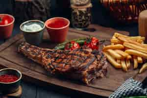 Free photo grilled beef steak with fries, grilled tomato, pepper and sauces