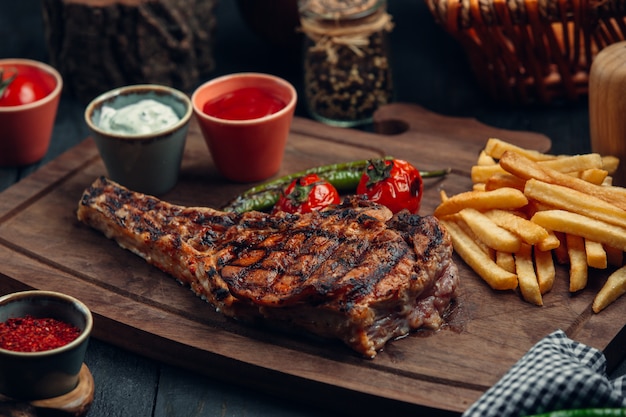 grilled beef steak with fries, grilled tomato, pepper and sauces