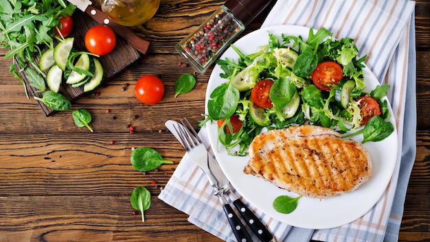 Foto gratuita petto di pollo alla griglia e insalata di verdure fresche - pomodori, cetrioli e foglie di lattuga. insalata di pollo. cibo salutare. disteso. vista dall'alto