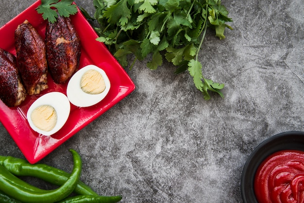 Grilled chicken breasts with boiled egg and ingredients on concrete background