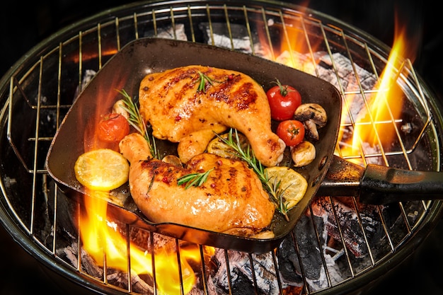 Grilled chicken Leg on the grill pan. appetizing grilled juicy chicken with golden brown crust served with tomato, lemon slices, mushroom, and rosemary. Selective focus. Healthy meal concept.