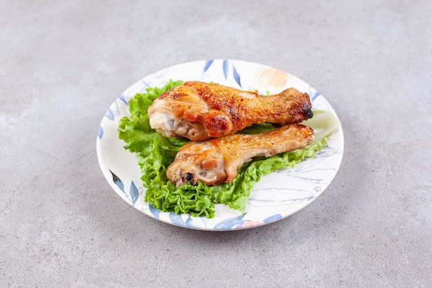 Мясо куриных ножек на гриле с салатом на белой тарелке