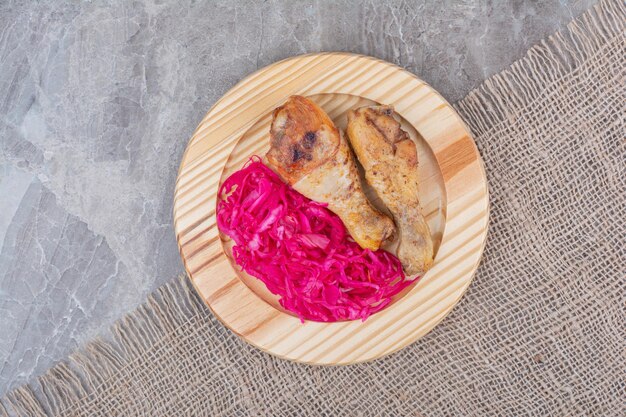 Foto gratuita cosce di pollo alla griglia e cavolo marinato sul piatto di legno.