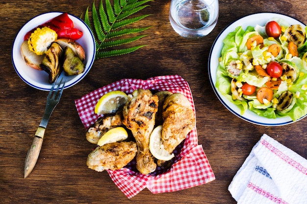 Free photo grilled chicken legs with lemon and salad