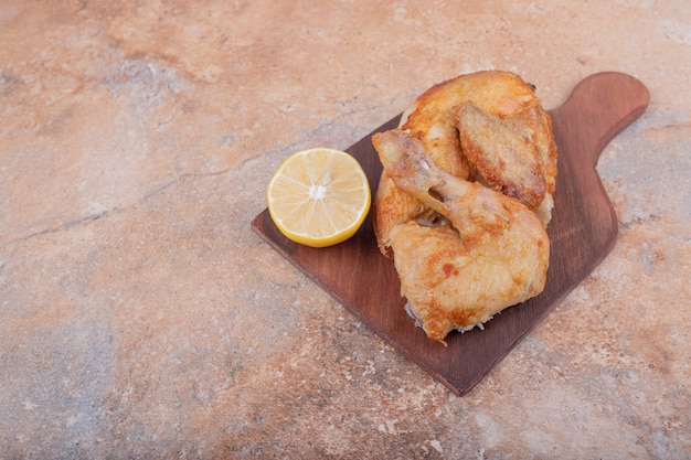 Grilled chicken meat with lemon on a wooden platter