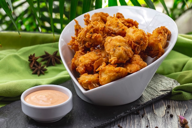 Grilled chicken nuggets in the bowl crackers spices and sauce side view