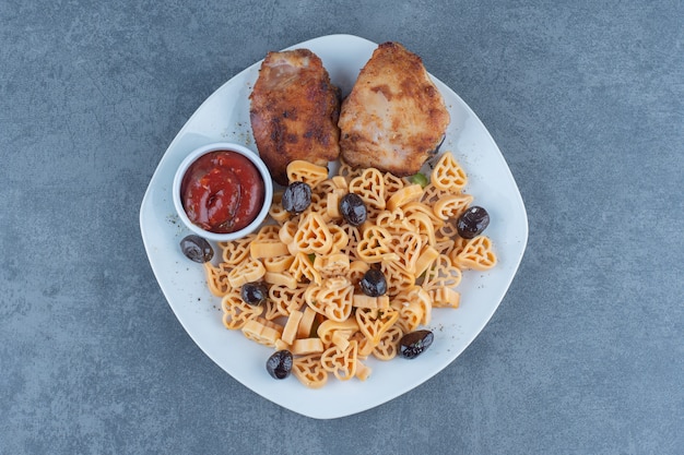 Grilled chicken parts and macaroni on white plate. 