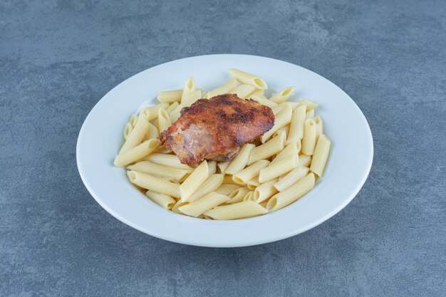 Grilled chicken and penne pasta in white bowl.