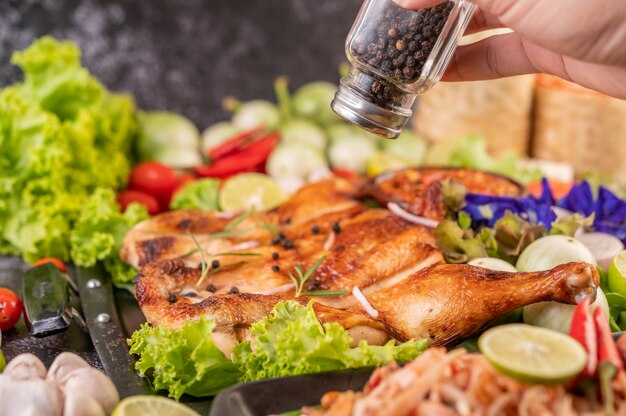 Grilled chicken on the plate with chili Garlic and sprinkled with pepper seeds.