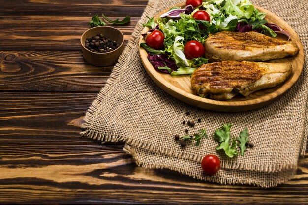 Grilled chicken and salad near black pepper