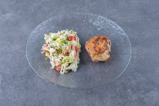 Grilled chicken and vegetable salad on glass plate.