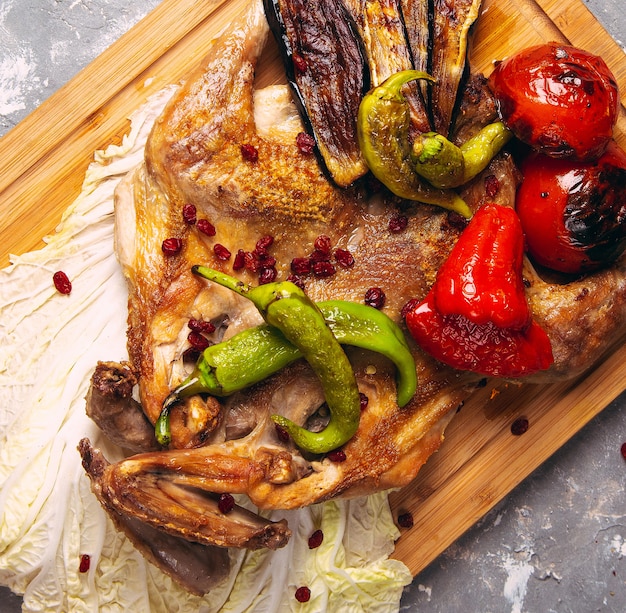 Grilled chicken and vegetables on the wooden board close-up. horizontal view from above 