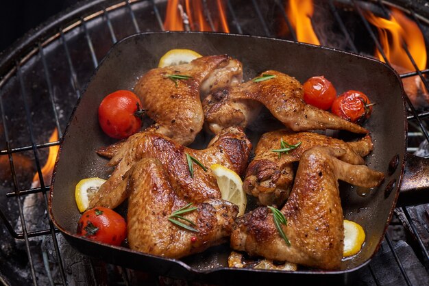 Куриные крылышки гриль на пламенном гриле с овощами гриль в соусе барбекю с перцем розмарином, солью.
