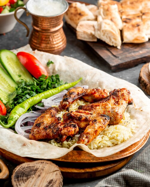 Grilled chicken wings served with rice and salad