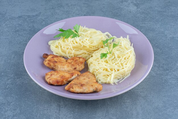Grilled chicken wings and spaghetti on purple plate.