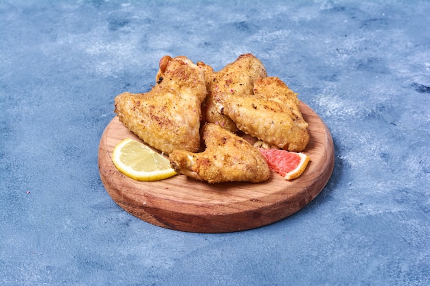 Grilled chicken wings on a wooden board on blue