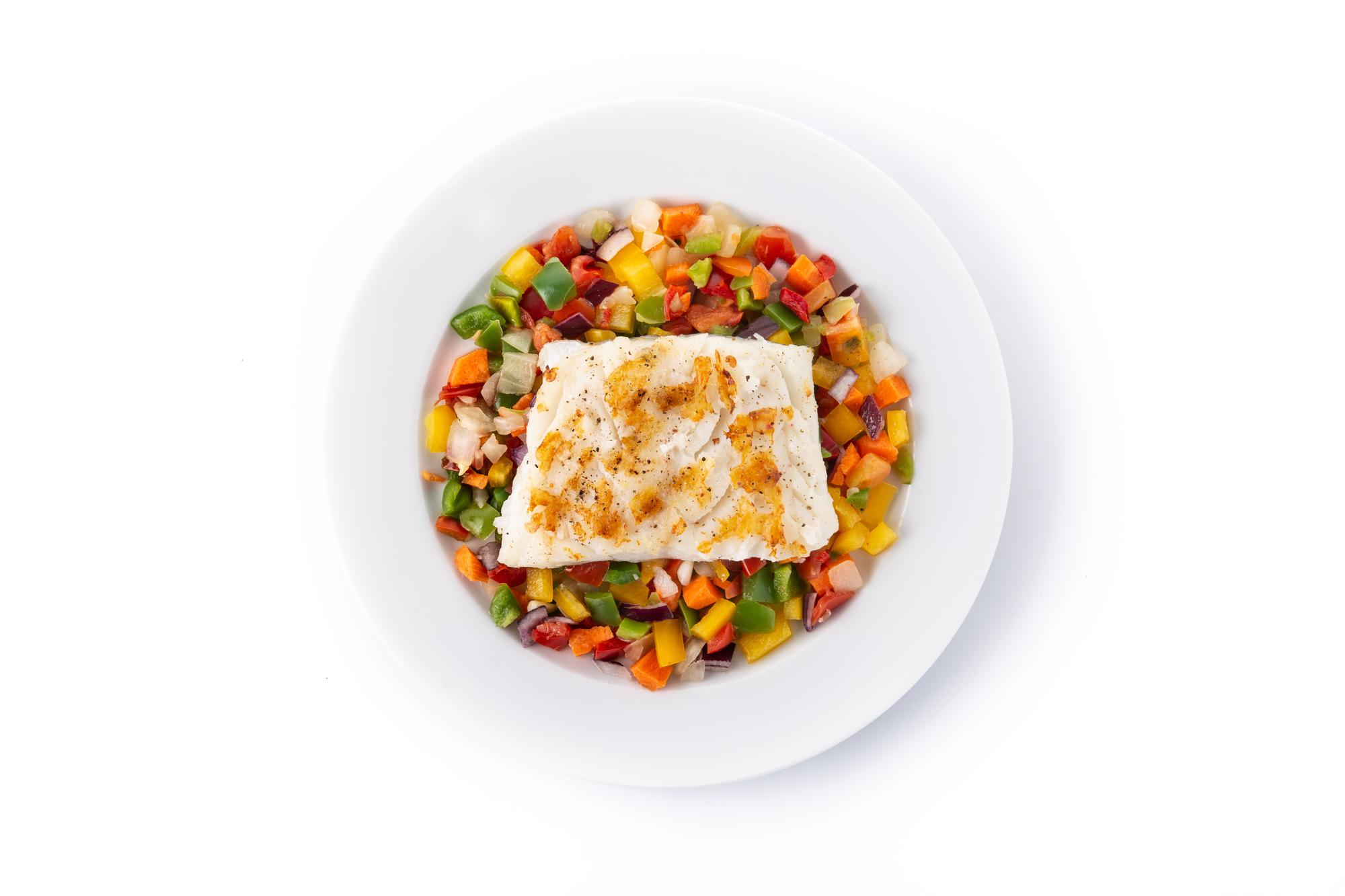 Grilled cod with vegetables in plate isolated on white background