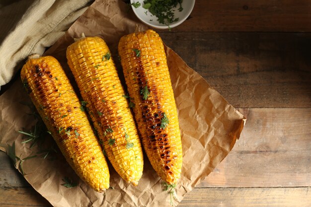 Grilled corn cobs on wood background.