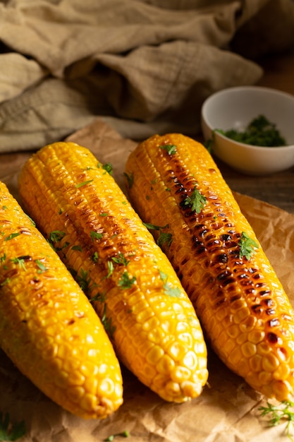 Grilled corn cobs on wood background.