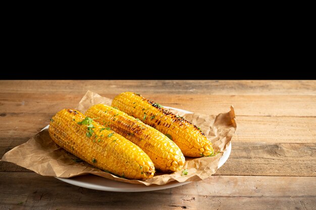 Grilled corn cobs on wood background.