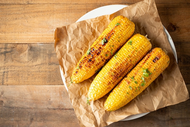 Free photo grilled corn cobs on wood background.