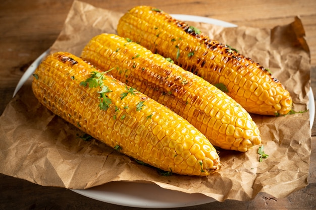 Grilled corn cobs on wood background.