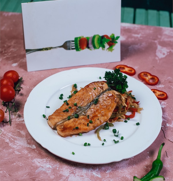 Grilled fish fillet with chopped herbs and tomatoes.