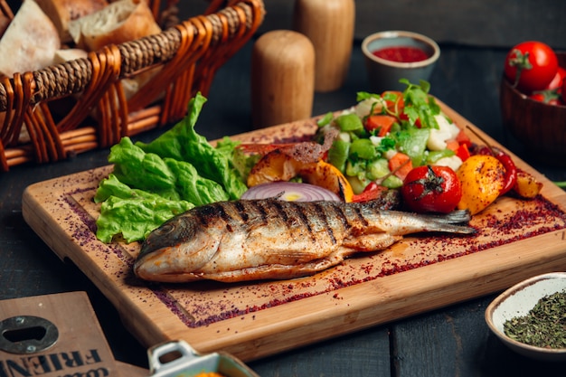 Free photo grilled fish with fresh vegetable salad, lettuce and sumac sprinkles