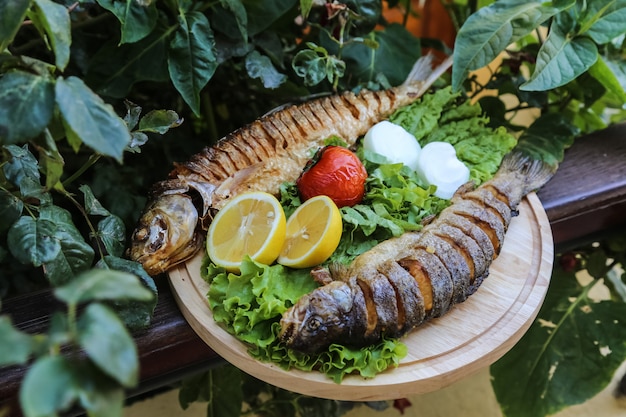 Рыба-гриль на деревянной доске салат помидор лук лимон
