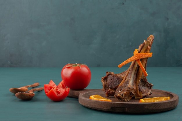 Grilled lamb chops with sliced vegetables on blue table.