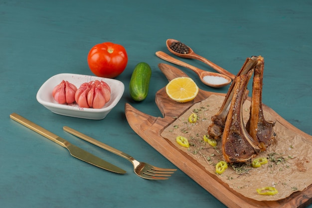 Free photo grilled lamb chops on wooden board with vegetables.