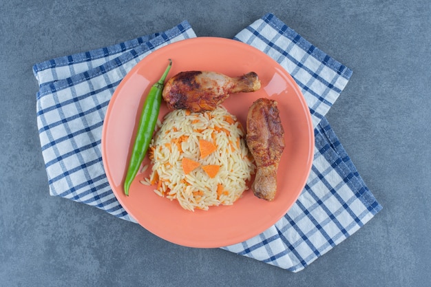 Grilled legs and seasoned rice on orange plate.