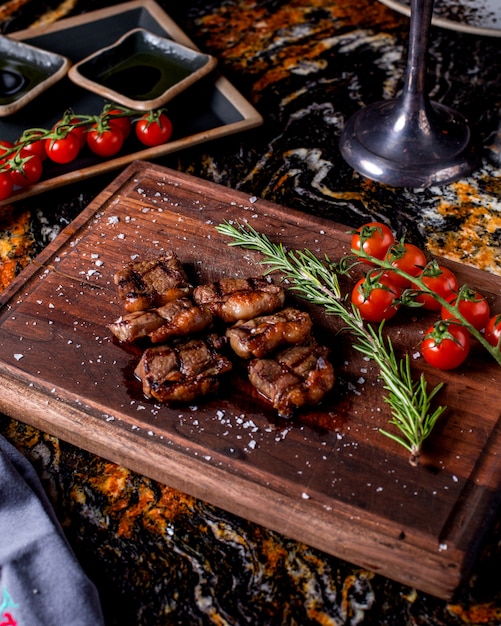 Grilled meat medallions served with rosemary sprig and tomatoes