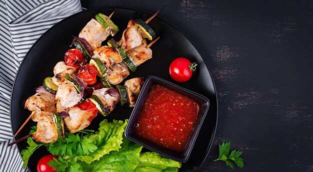 Grilled meat skewers, chicken shish kebab with zucchini, tomatoes and red onions