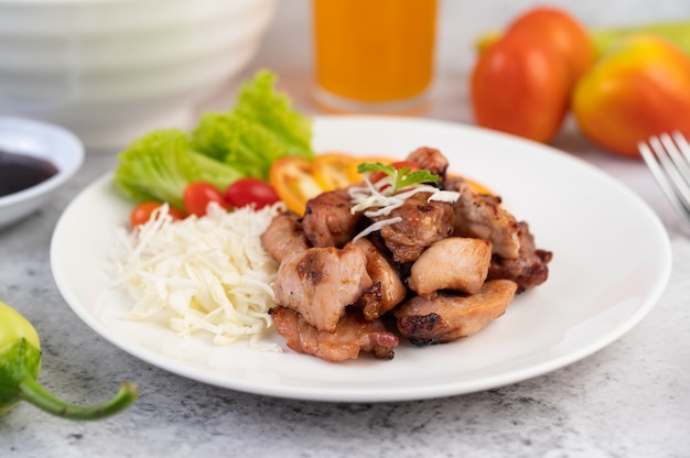 Grilled pork cutlet with tomatoes and salad, arranged in a white dish.