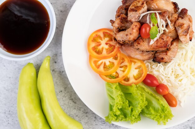 Free photo grilled pork cutlet with tomatoes and salad, arranged in a white dish.