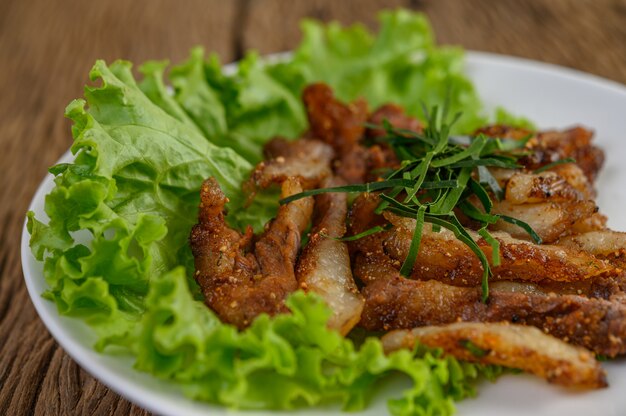 Grilled pork neck on a white plate on a wooden table