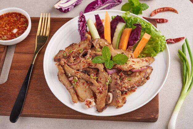 Grilled pork salad thai food with herbs and spices ingredients, tradition northeast food delicious with fresh vegetables, Hot and spicy slice grilled pork menu asian food. Grilled pork with spicy dip.