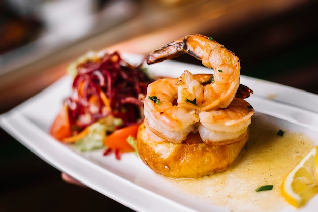 Grilled prawns in lemon sauce with tomato lettuce greens carrot side view