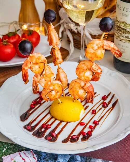 Grilled prawns on wooden sticks lemon pomegranate side view