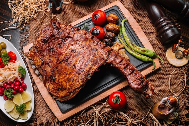 Foto gratuita costole arrostite sulla vista superiore della patata del pepe del pomodoro del bordo di legno