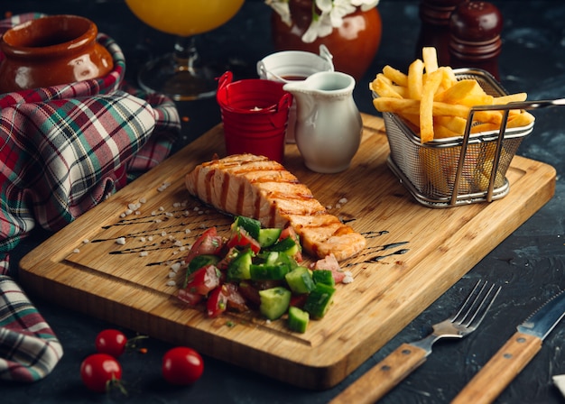 grilled salmon fillet with french fries, mayo, ketchup and fresh salad