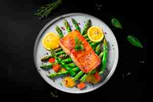 Free photo grilled salmon with asparagus on white plate isolated on black background