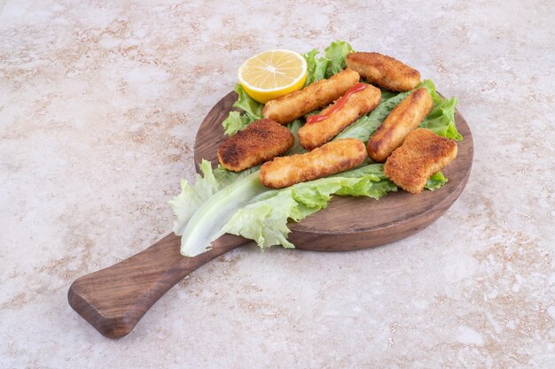 Grilled sausages, cheese sticks and chicken nugges on a lettuce leaf.
