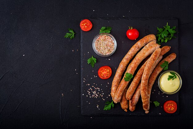 Grilled sausages on dark background. Oktoberfest. Flat lay. Top view