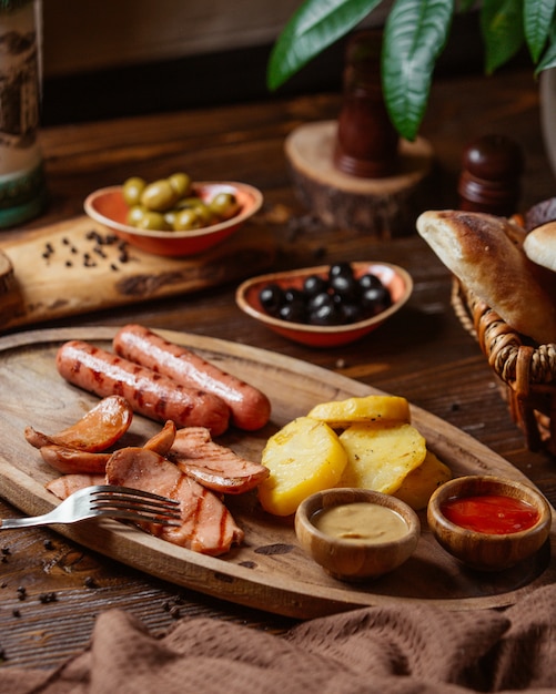 grilled sausages plate with fried potatoes and mustard and ketchup