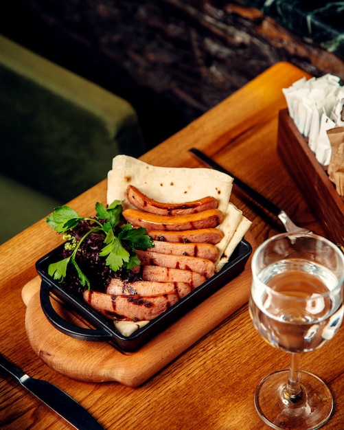 Grilled sausages served with flatbread and green herbs