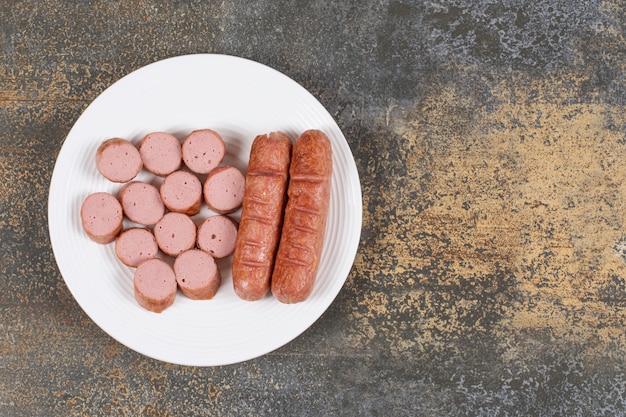 Salsicce affettate alla griglia sul piatto bianco.